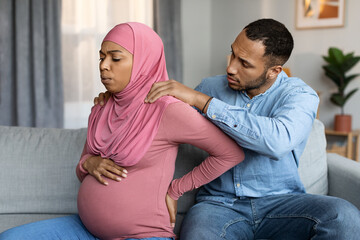 Loving husband making massage to his pregnant black muslim wife at home