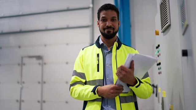 Young industrial worker operating cnc machine at metal machining industry