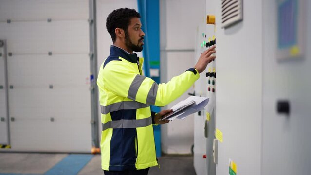 Young industrial worker operating cnc machine at metal machining industry