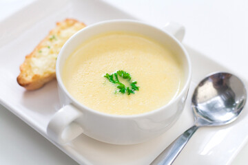 Delicious corn soup In a white bowl served with bread.
