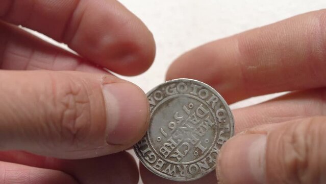 Mature man's hands holding a Ancient European Siver Coin And Cleans It With A Cotton Bud