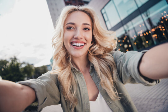 Self portrait of attractive cheerful wavy haired girl spending sunny day weekend at shopping center mall outside