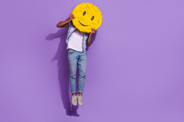 Full length photo of positive cheerful man wear jeans jumping empty space holding smile pinata...