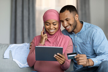 E-Commerce Concept. Pregnant Muslim Spouses Using Digital Tablet And Credit Card
