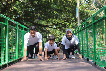Sporty muslim mother father and son getting ready to run in a crouch start position. Outdoor sports and fitness family. Running and jogging.