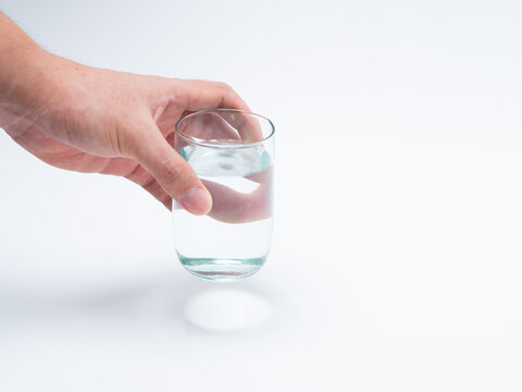 Hand holding a glass of water. Drinking 8 glasses of water per day is healthy.