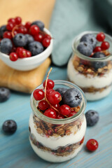 Delicious yogurt parfait with fresh berries on turquoise wooden table, closeup