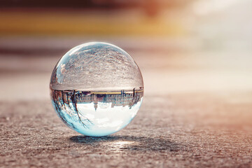 A glass ball with a reflection of a building lies on a stone surface