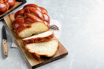 Cut homemade braided bread on grey table, space for text. Traditional Shabbat challah - obrazy, fototapety, plakaty