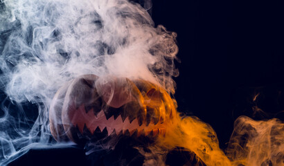 Composition of halloween carved pumpkin with smoke and orange light on black background