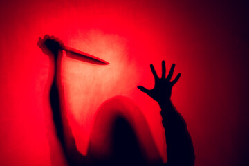 Composition of silhouette of woman holding knife on red background