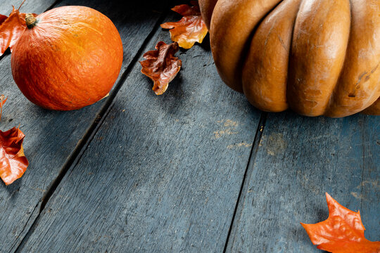 Composition of pumpkins and autumn leaves on wooden background
