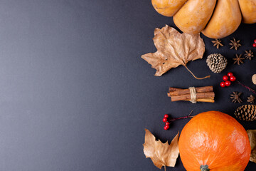 Composition of pumpkins with autumn leaves, pinecones and spices on black background