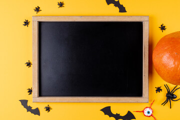 Composition of frame with copy space, halloween decorations and pumpkin on orange background