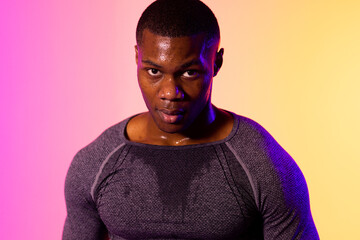 Portrait of african american male runner with sportswear over pink lighting