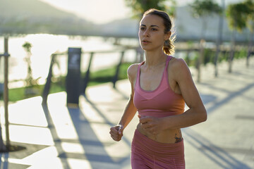 Portrait of fitness healthy woman running on road at promenade. Jogging workout wellness concept