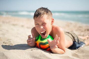 Teenage boy on the beach with a ball. Positive emotions. Relax. Joyful face.