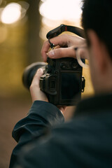 A man holds the mirrorless camera with two hands and the screen is visible. Concept of a hobby...