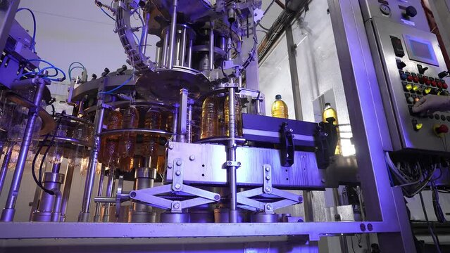 Production and bottling of beverages carbonated lemonade, soda or beer in plastic bottles on automatic conveyor on industrial plant. Food industry concept. Manufacturing of bottled drinks. blue light
