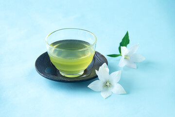 冷たい緑茶と白いキキョウの花