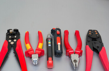 Red professional electrician tools on silver grey background.