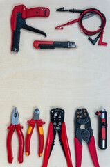 Professional electrician tools on wood background. All tools with red handles.