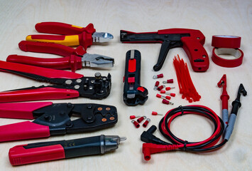 Red professional electrician tools on light wood background.