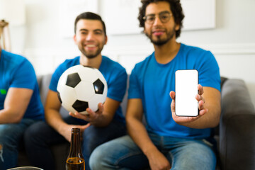Sports fans texting and showing the smartphone while enjoying a soccer world cup on tv