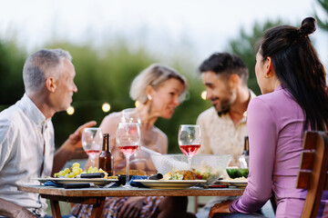 Friends having gossip conversation telling whisper secret during summer dinner outdoors