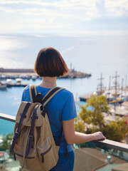 Fototapeta premium travel to Turkey, old town Antalya Kaleci. Happy asian female tourist traveller with backpack walks in old city. Woman on lookout over the old town and the port from viewpoint