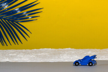 blue car on the road by the beach driving, sunny summer day, blue palm leaf in the corner of the background, creative tropical design, travel by beautiful places