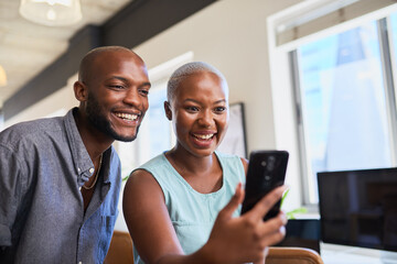 Two Black colleagues laugh on a video call on mobile phone