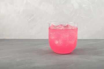 Pink refreshing iced drink. Summer fruit cocktail in clear glass on grey background. Pink lemonade...