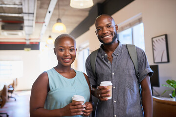 Two Black colleagues arrive at the office with coffee and smiles