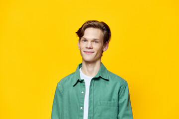 Obraz na płótnie Canvas portrait of a happy guy in a green shirt on a yellow background