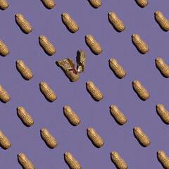 Peanut pattern on a lilac background, one broken peanut. Flat lay. Minimal concept.