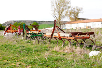 Fototapeta na wymiar Photograph of old agricultural machinery, four old plows that are abandoned, disused and rusting. Decadence of agriculture. Selective focus