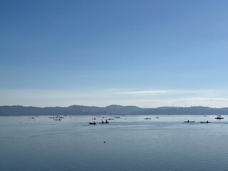 Beautiful Calm Water Reflection Lake and Fisherman working fishing on Boats with Blue Sky and Sunny Weather Clear Horizon