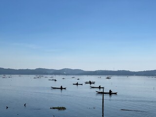 Beautiful Calm Water Reflection Lake and Fisherman working fishing on Boats with Blue Sky and Sunny Weather Clear Horizon