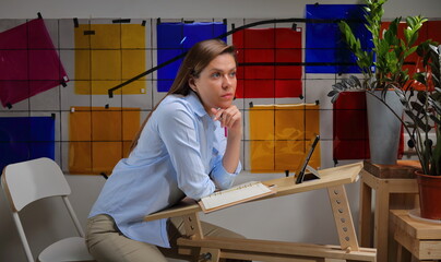 Woman designer student  learning in classroom with color palette on wall.