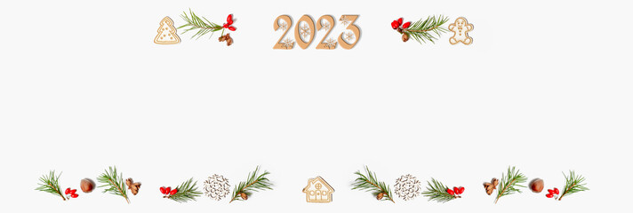 Banner. Christmas frame. Flat lay of wooden numbers 2023, fir branches, red berries, new Year decoration on a white background.