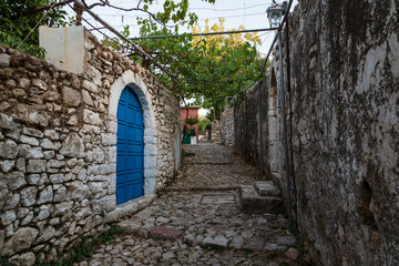 Fototapeta na wymiar Classic traditional Mediterranean village house door and rock pavement Mediterranean style. picture taken in Albanian city of Himara the old part. Blue doors and roads in the village. Albania