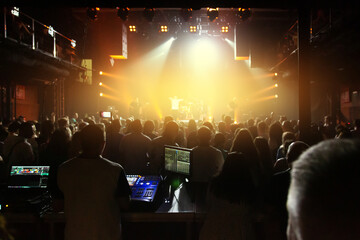 Crowd of spectators in front of the stage at a concert of a popular band in the concert club.