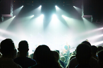 Silhouette of a crowd of spectators in front of the stage on a background of bright spotlights.