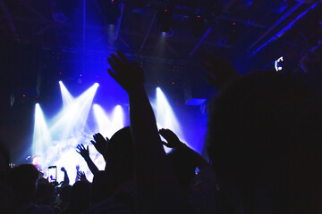 Silhouettes of a concert crowd in front of an illuminated stage in a nightclub. Smoke, concert...