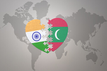puzzle heart with the national flag of india and maldives on a world map background.Concept.