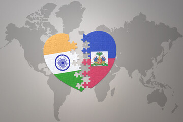puzzle heart with the national flag of india and haiti on a world map background.Concept.