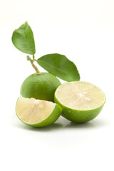 Close-up of fresh green organic lemon (Citrus limon) and sliced lemon  with leaf  isolated over white.
