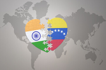 puzzle heart with the national flag of india and venezuela on a world map background.Concept.