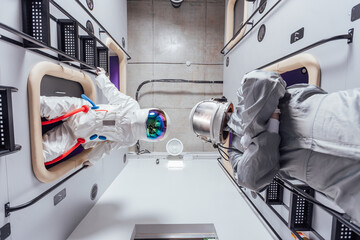 Portrait of astronauts in spacesuits in the sleeping module of the capsule hotel. View from below